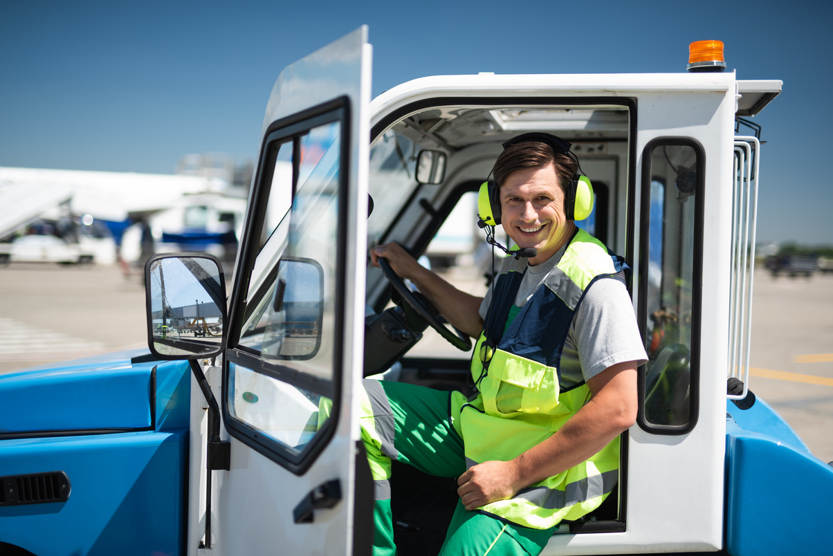 Smiling airport worker sitting in vehicle